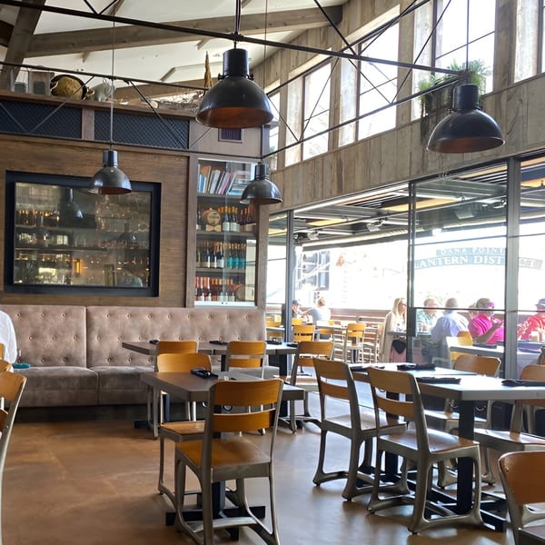 The Craft House dining room features industrial lighting, wooden accents, and a window view of patrons.