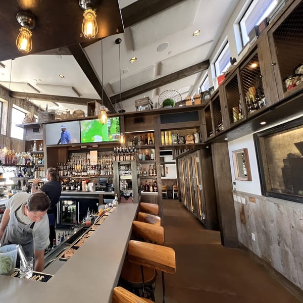 Craft House bar with bartenders, liquor bottles, TVs, and wooden bar stools.