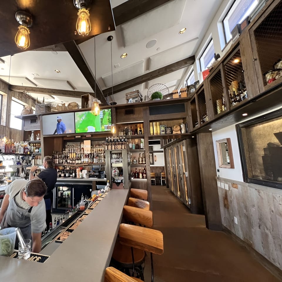 Craft House bar with bartenders, liquor bottles, TVs, and wooden bar stools.